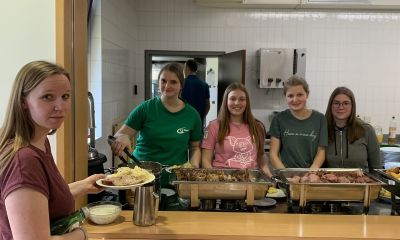 Speisen werden von vier Mädchen auf Tellern portioniert ausgegeben