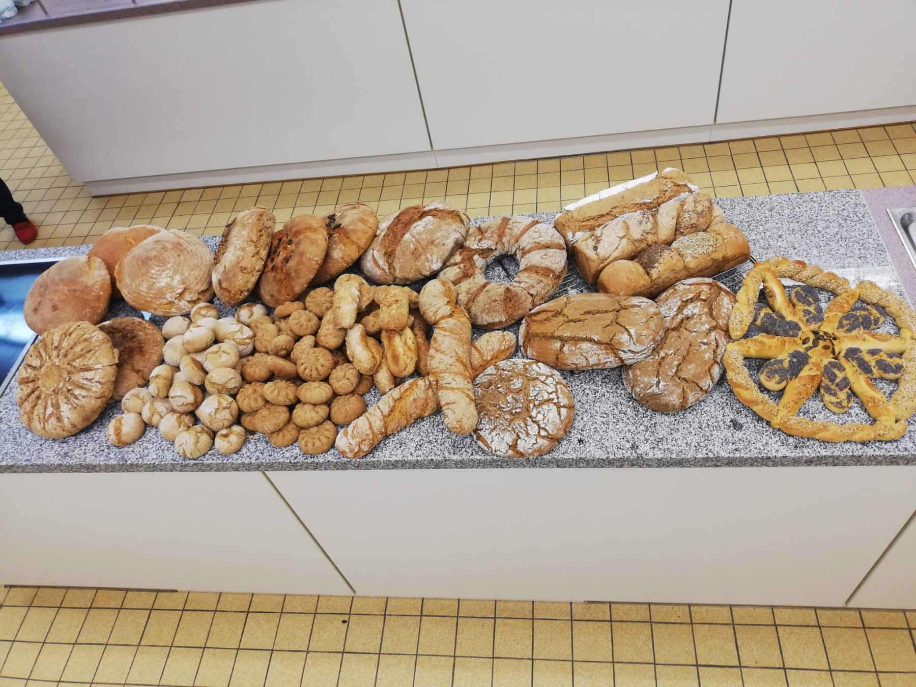 verschiedene Brot- und Gebäcksorten selbst gebacken liegen auf einem Tisch