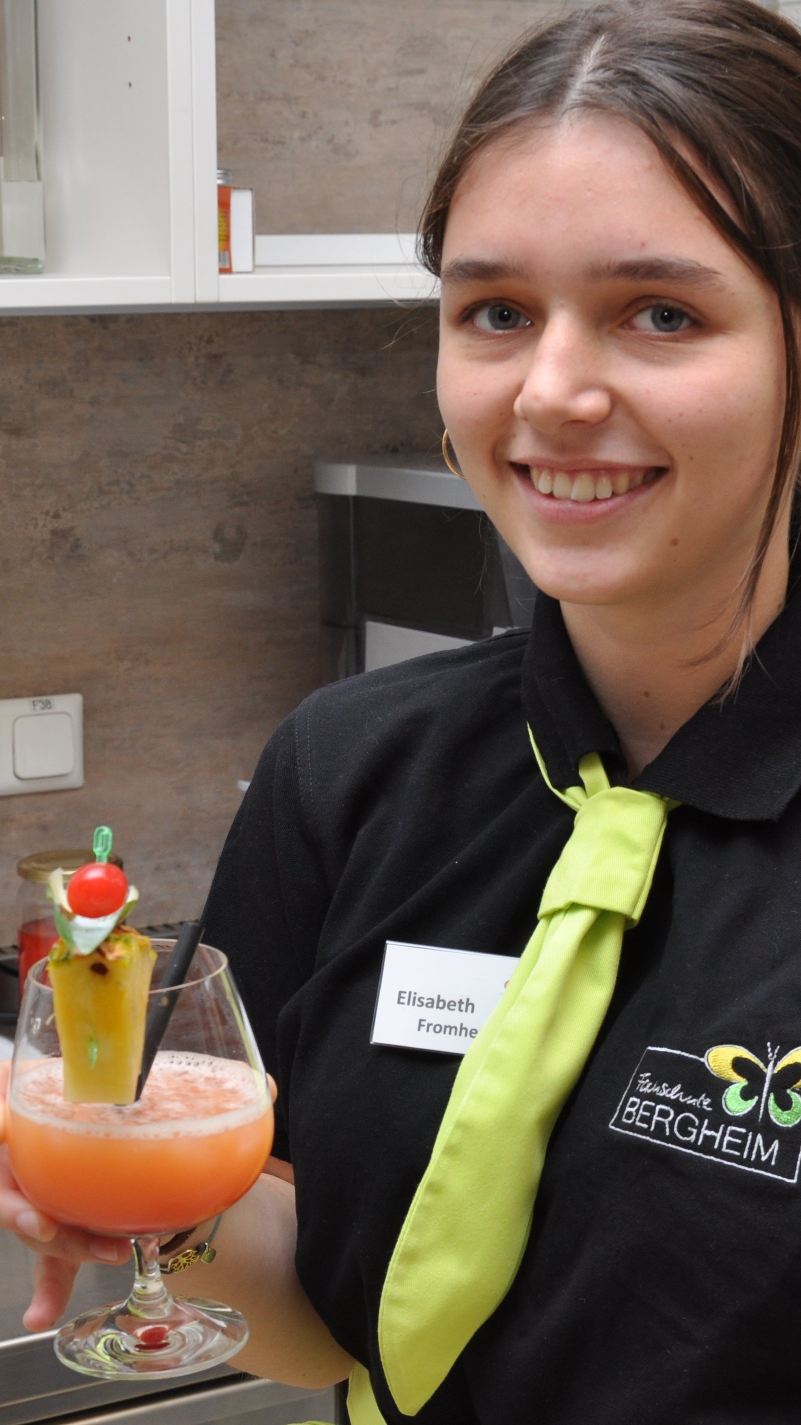 Mädchen in Servicekleidung präsentiert lächeln den fertigen Cocktail
