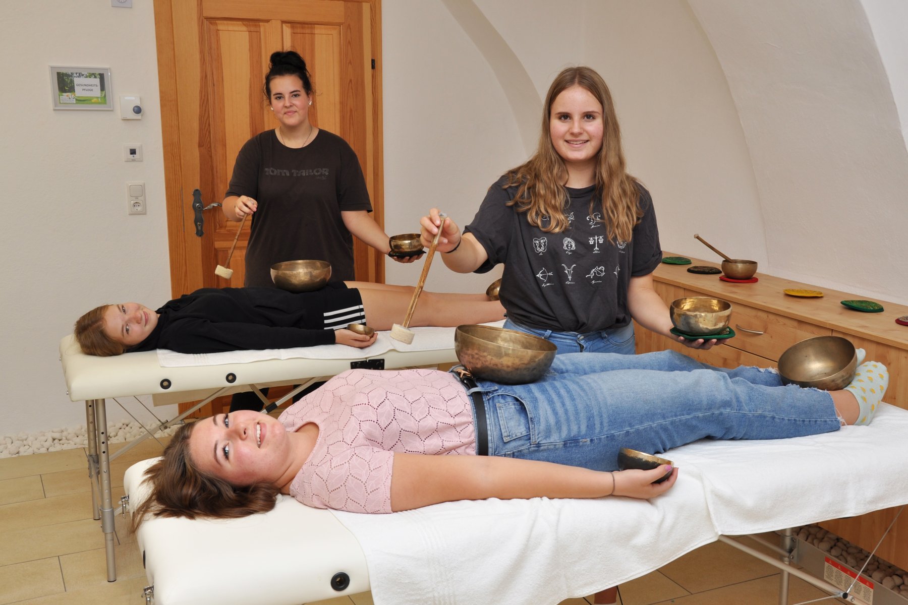 2 Mädchen auf Massageliegen bekommen Massage mit Klangschalen
