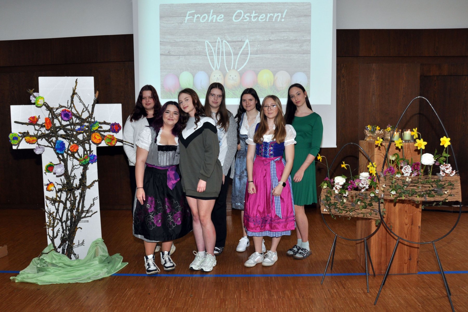Mädchengruppe steht zwischen österlicher Großraumdekoration und wünscht frohe Ostern